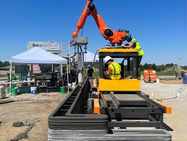 a robotic arm releasing concrete on a construction site